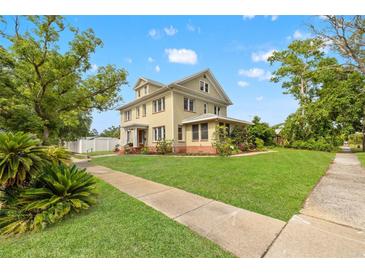 Charming two-story home featuring a lush green lawn, mature trees, and inviting walkway at 241 72Nd N St, St Petersburg, FL 33710