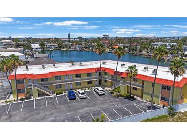 Waterfront condo building with palm trees, parking, and canal views offers relaxed coastal living at 4103 Gulf Blvd # 107, St Pete Beach, FL 33706