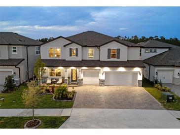 Elegant two-story home featuring a paved driveway and a welcoming front porch with cozy seating at 7819 Notched Pine Bnd, Wesley Chapel, FL 33545