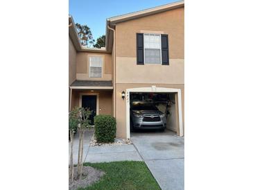 Two-story townhome with a one-car garage, dark shutters, and manicured landscaping at 8423 Edgewater Place Blvd, Tampa, FL 33615
