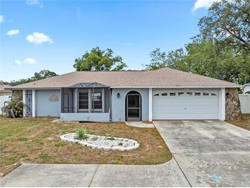 Charming single-story home featuring a screened porch, two-car garage, and well-maintained landscaping in a suburban neighborhood at 9107 Spring Hill Dr, Spring Hill, FL 34608