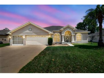 Charming single-story home featuring a manicured lawn, arched windows, and a spacious two-car garage at 9219 Irondale Ln, Hudson, FL 34667