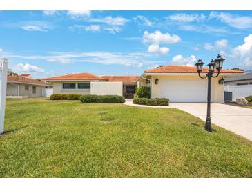 Charming home with a well-manicured lawn and a driveway leading to an attached garage at 13821 Joyce Dr, Largo, FL 33774