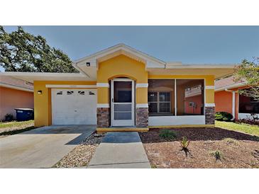 Charming single-story home featuring a yellow exterior, screened porch, attached garage, and well-maintained landscaping at 1850 Fuller Dr, Clearwater, FL 33755