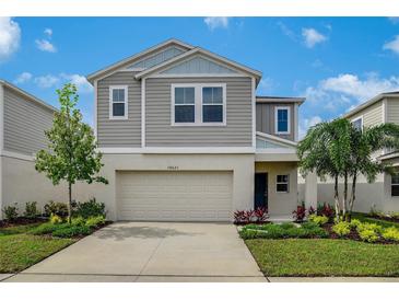 Charming two-story home featuring a two-car garage, well-maintained lawn, and colorful landscaping under a beautiful sky at 37122 Sagemoor Dr, Zephyrhills, FL 33541