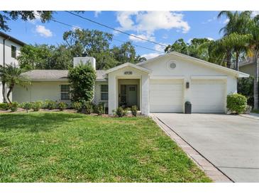 Charming single-story home with a lush front lawn, blooming flowers, and a two car garage at 4705 W Estrella St, Tampa, FL 33629