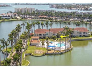 An aerial view of condo community with pool, palm trees, and a lake in the background at 6100 Bahia Del Mar Cir # 105, St Petersburg, FL 33715