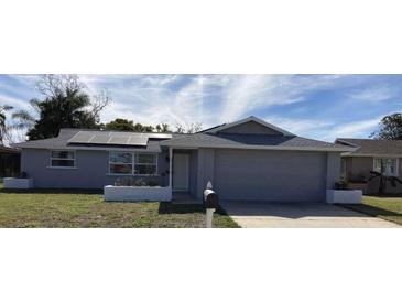 Charming single-story home with an attached garage, solar panels, and well-maintained landscaping at 7524 Oakshire Dr, Port Richey, FL 34668