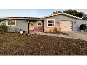 Charming single-story home with a well-manicured lawn, updated paint, and cozy front porch seating at 821 Karen St, Palm Harbor, FL 34684