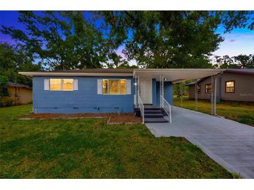 Charming blue home featuring a covered carport, well-maintained lawn, and a welcoming facade at 1304 N Ferrell St, Plant City, FL 33563