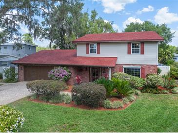 Charming two-story home featuring a red roof, well-maintained landscaping, and an attached garage at 18712 Lakeshore Dr, Lutz, FL 33549