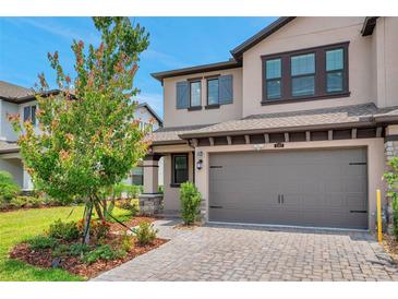 Charming two-story home featuring a brick driveway, attached two-car garage, and beautifully landscaped front yard at 5103 San Martino Dr, Wesley Chapel, FL 33543