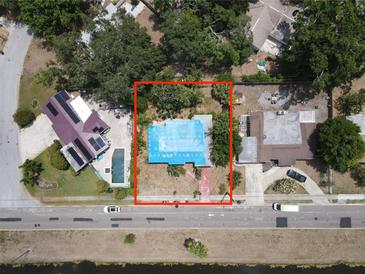 Aerial view of the property with a blue tarp covered roof, surrounded by mature trees and neighboring houses at 6715 16Th N St, St Petersburg, FL 33702
