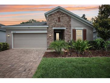 Charming single-story home with a stone facade, well-manicured lawn, and two-car garage at 10625 Cardera Dr, Riverview, FL 33578