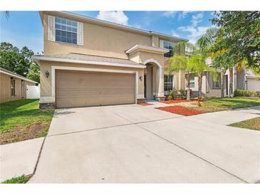 Charming home with attached two-car garage, manicured lawn, and mature palm trees at 13174 Royal Pines Ave, Riverview, FL 33579