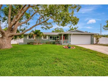 Charming single-story home featuring a lush green lawn, mature trees, and a two-car garage at 1398 Lemon St, Clearwater, FL 33756
