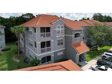 Gray condo building with orange tile roof, white balcony railings, and well-maintained landscaping at 18001 Richmond Place Dr # 330, Tampa, FL 33647