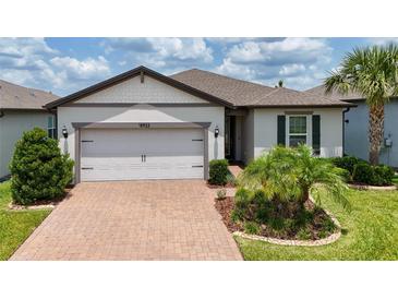Charming single-story home featuring a two-car garage, landscaped yard, and brick-paved driveway at 18933 Sailors Delight Pass, Land O Lakes, FL 34638