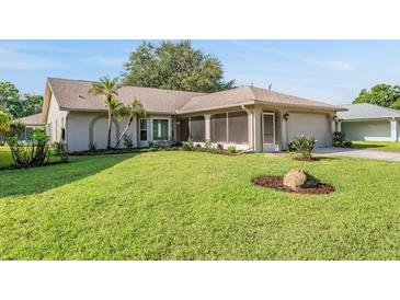 Single-story home with a well-manicured front yard, mature landscaping, and a screened entryway at 3956 Tarpon Pointe Cir, Palm Harbor, FL 34684