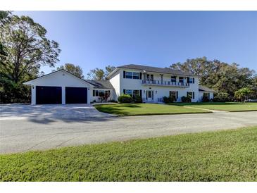 Two-story home with a balcony, dark shutters, two-car garage and driveway situated on a well-kept lawn at 1089 Virginia St, Dunedin, FL 34698