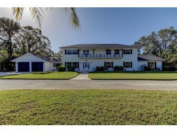 Elegant two-story home features a charming balcony, manicured lawn, and a two car attached garage at 1089 Virginia St, Dunedin, FL 34698