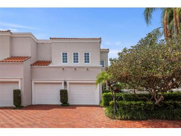 Mediterranean style home featuring a two-car garage, red brick driveway, and well-manicured landscaping at 4941 Bayshore Blvd, Tampa, FL 33611
