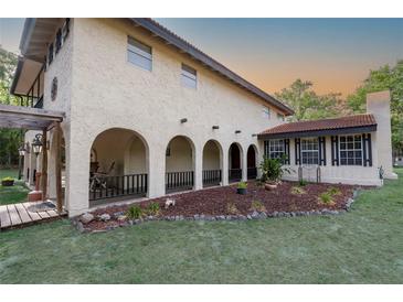 Charming stucco home boasting arched loggia, landscape beds, and a covered entry for welcoming curb appeal at 12311 Oakwood Dr, Hudson, FL 34669