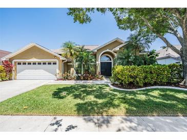 Inviting home featuring a manicured lawn, lush landscaping, and a two-car garage at 12421 Seabrook Dr, Tampa, FL 33626