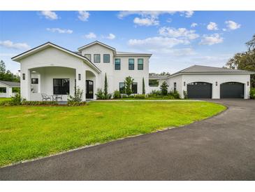 Beautiful two-story white home with manicured lawn and attached three car garage at 13711 Lussier Ln, Spring Hill, FL 34610