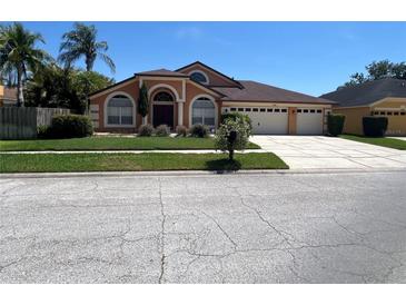 Charming single-story home with a well-manicured lawn and a three-car garage on a sunny day at 18104 Sweet Jasmine Dr, Tampa, FL 33647