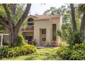 Inviting two-story home featuring a balcony, tile roof, and lush landscaping at 307 Los Prados Dr # 307, Safety Harbor, FL 34695