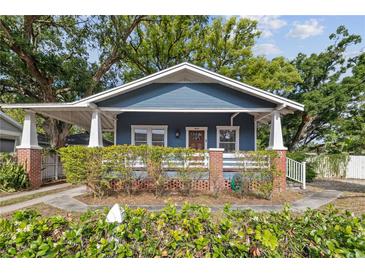 Charming blue two-story home features a covered porch, well-manicured landscaping and mature trees at 4016 N Seminole Ave, Tampa, FL 33603