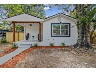 Charming home with front porch, natural wood post accents, fresh paint, and landscaped front yard at 8704 N Brooks St, Tampa, FL 33604
