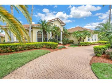 Stunning Mediterranean-style home with lush landscaping, a brick driveway and a barrel tile roof at 9818 Tree Tops Lake Rd, Tampa, FL 33626
