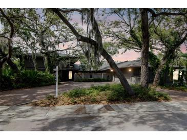 Charming exterior view of home featuring mature landscaping and a spacious driveway at 1296 Weybridge Ln, Dunedin, FL 34698