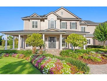 Stately two-story home featuring a welcoming front porch and beautifully landscaped front yard with colorful flowers at 17129 Breeders Cup Dr, Odessa, FL 33556