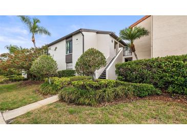 Charming condo exterior with manicured landscaping, mature palms, and a private entrance at 2597 Countryside Blvd # 206, Clearwater, FL 33761