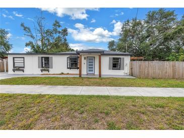 Charming single-story home with a well-manicured lawn and a modern, updated facade, and a light blue front door at 4432 W Mccoy St, Tampa, FL 33616
