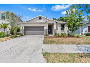 Charming single-story home featuring a well-manicured lawn and stone veneer accents at 10563 Laguna Plains Dr, Riverview, FL 33578
