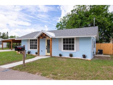 Charming single-story home with blue stucco exterior, decorative wooden accents, and well-manicured lawn at 1114 Michigan N Dr, Dunedin, FL 34698
