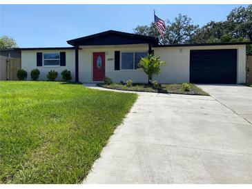 Charming one story home with large front yard, colorful door, dark shutters and an American flag at 12907 College Hill Dr, Hudson, FL 34667