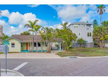 Inviting coastal home with covered porch, manicured landscaping, and paved driveway entrance at 18198 3Rd E St, Redington Shores, FL 33708
