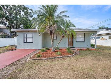 Charming single-story home featuring a red driveway, mature palm trees, and tidy landscaping at 3308 W Walnut St, Tampa, FL 33607