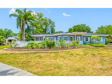 Beautiful single Gathering home with well-manicured lawn, mature landscaping, and a decorative white fence along the front of the property at 401 Whitcomb Blvd, Tarpon Springs, FL 34689