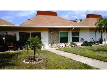 Charming single-story condo featuring a well-maintained lawn and covered front porch at 4345 Tahitian Gardens Cir # C, Holiday, FL 34691