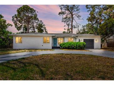 Charming single-story home featuring a gray driveway, minimalist landscaping and stylish blue door at 6120 5Th N Ave, St Petersburg, FL 33710
