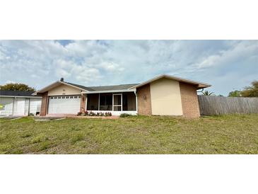 Ranch-style home featuring an attached two-car garage and a screened-in patio at 7012 Pin Cherry Ln, Port Richey, FL 34668
