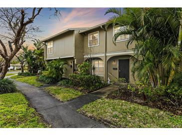 Inviting townhouse featuring lush landscaping and a charming covered entryway at 7606 Woodbridge Blvd, Tampa, FL 33615