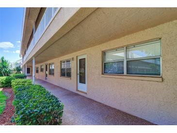 Exterior view of condo with neutral stucco siding, walkway, and green shrubs along the front at 10037 62Nd N Ter # 9, St Petersburg, FL 33708