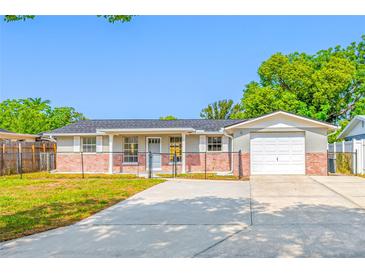 Charming single-story home featuring a gray facade with brick accents and well-manicured lawn at 10825 Oakdale Ave, Port Richey, FL 34668